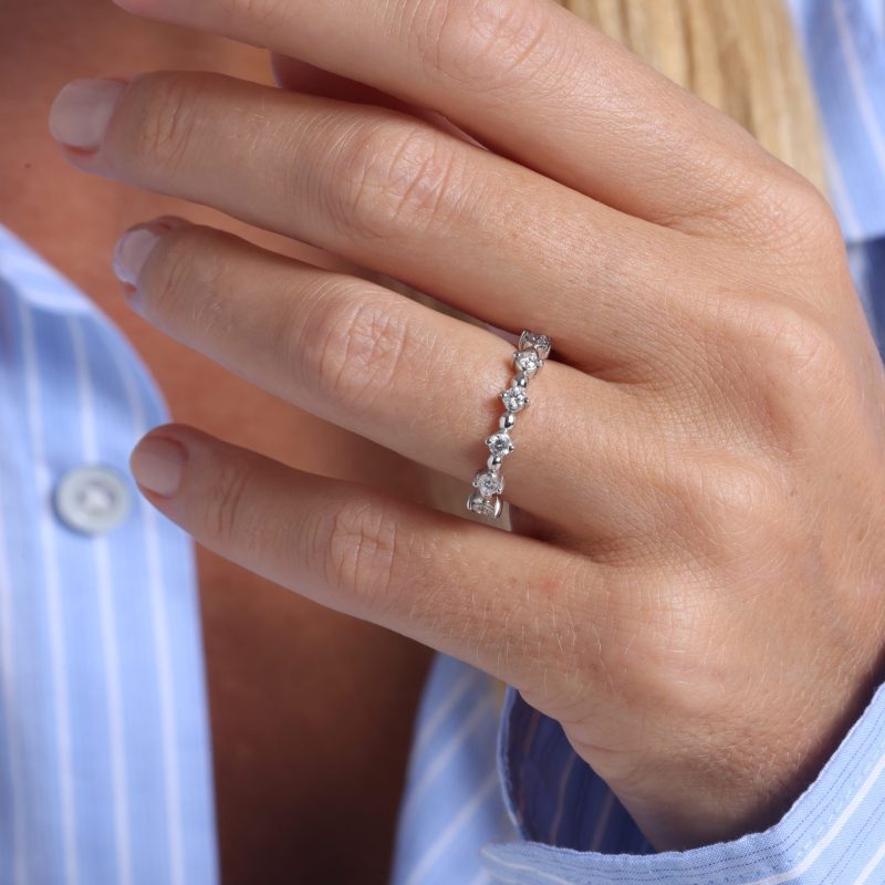 img src = "bague.jpg" alt = "alliance en or blanc sertie de diamants ronds en tour complet sur la main d'un mannequin"
