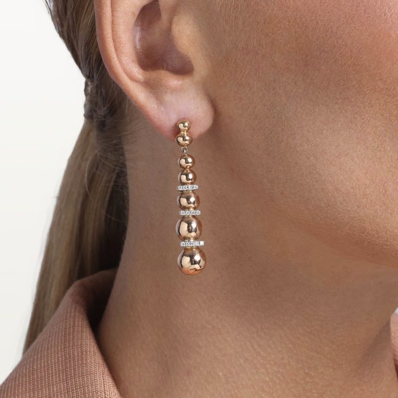 img src="boucles.jpg" alt="boucles d’oreilles pendantes en or rose avec sphères polies et diamants design moderne sur mannequin"