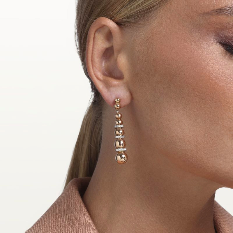 img src="boucles.jpg" alt="boucles d’oreilles pendantes en or rose avec sphères polies et diamants design moderne sur mannequin"