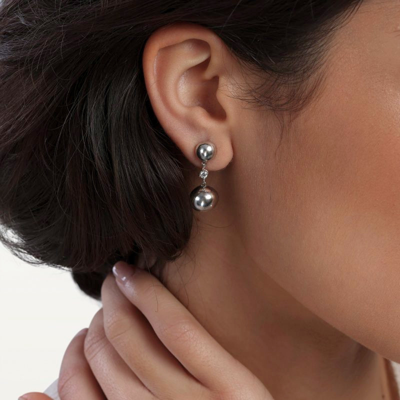 img src="boucles.jpg" alt="boucles d’oreilles pendantes en or blanc avec sphères polies et diamants sur mannequin"