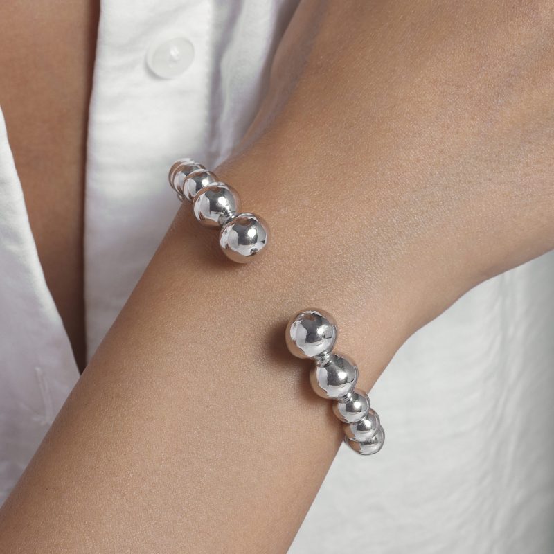 img src="bracelet.jpg" alt="bracelet jonc ouvert en or blanc avec perles sphériques design minimaliste sur mannequin"