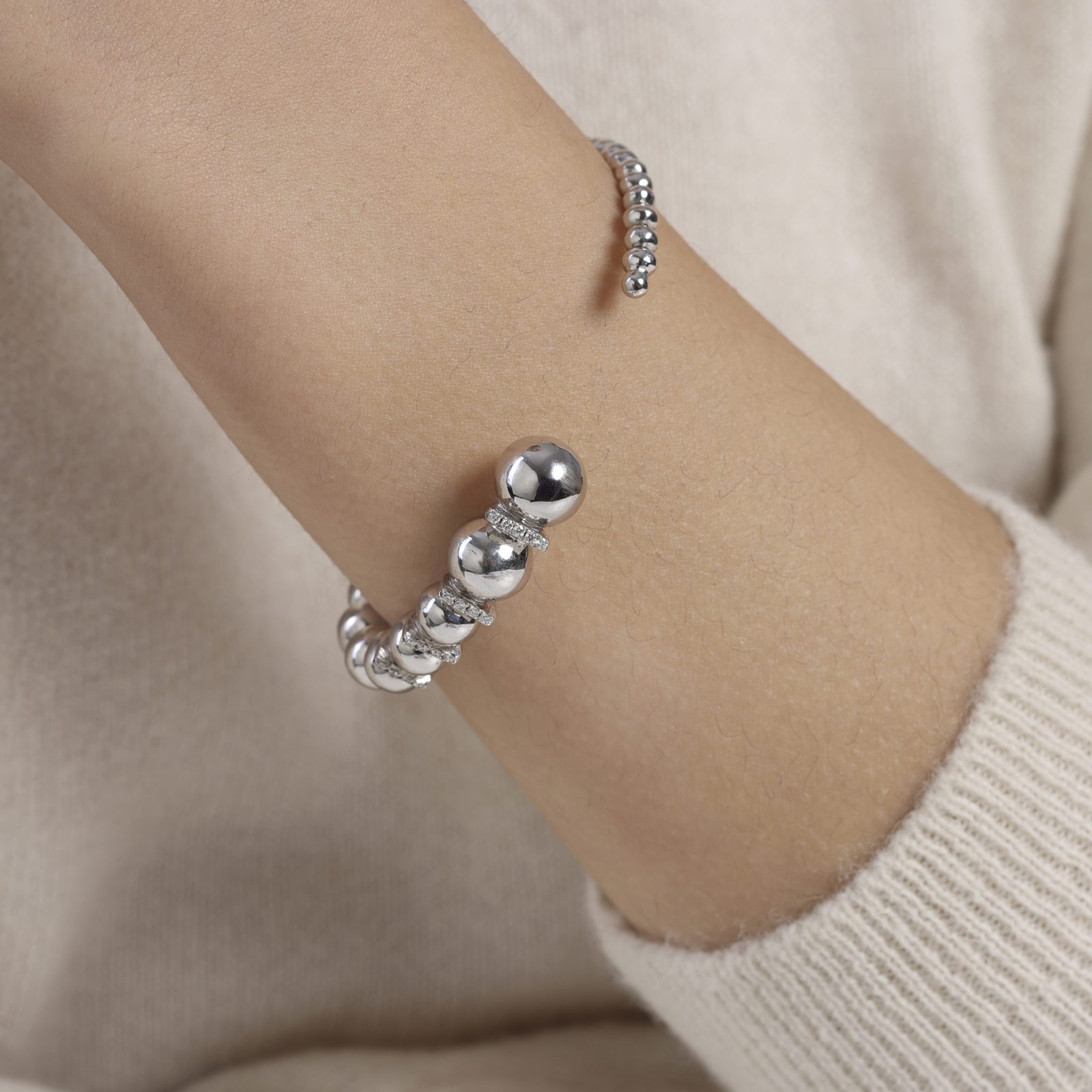 img src="bracelet.jpg" alt="bracelet jonc ouvert en or blanc avec boules sphériques polies design minimaliste sur mannequin"