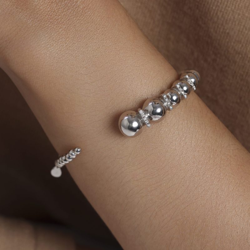 img src="bracelet.jpg" alt="bracelet jonc ouvert en or blanc avec boules sphériques polies design minimaliste sur mannequin"