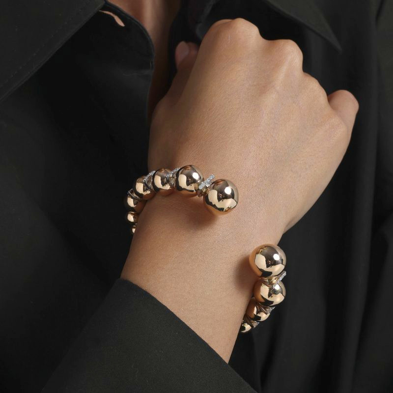 img src="bracelet.jpg" alt="bracelet jonc ouvert en or rose avec sphères polies et diamants design moderne sur mannequin"