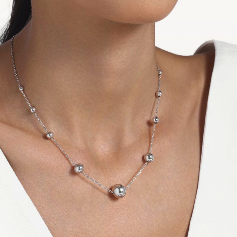 img src="collier.jpg" alt="collier en or blanc avec sphères polies design minimaliste sur mannequin"