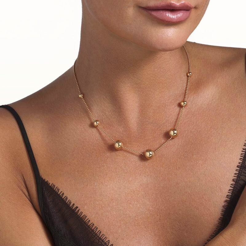 img src="collier.jpg" alt="collier en or rose avec sphères polies design minimaliste sur mannequin"