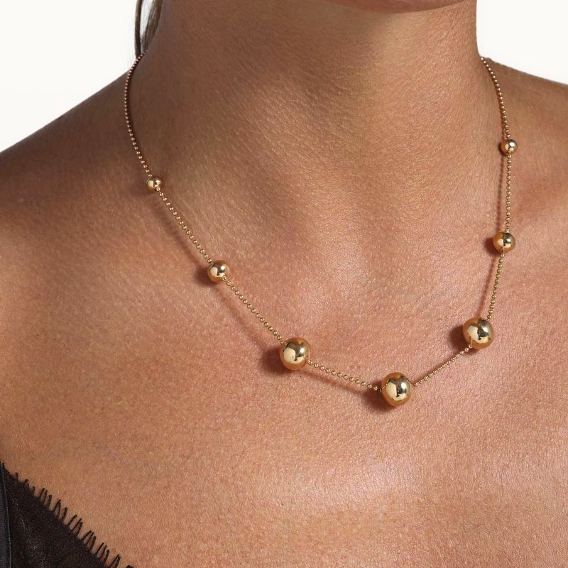 img src="collier.jpg" alt="collier en or rose avec sphères polies design minimaliste sur mannequin"